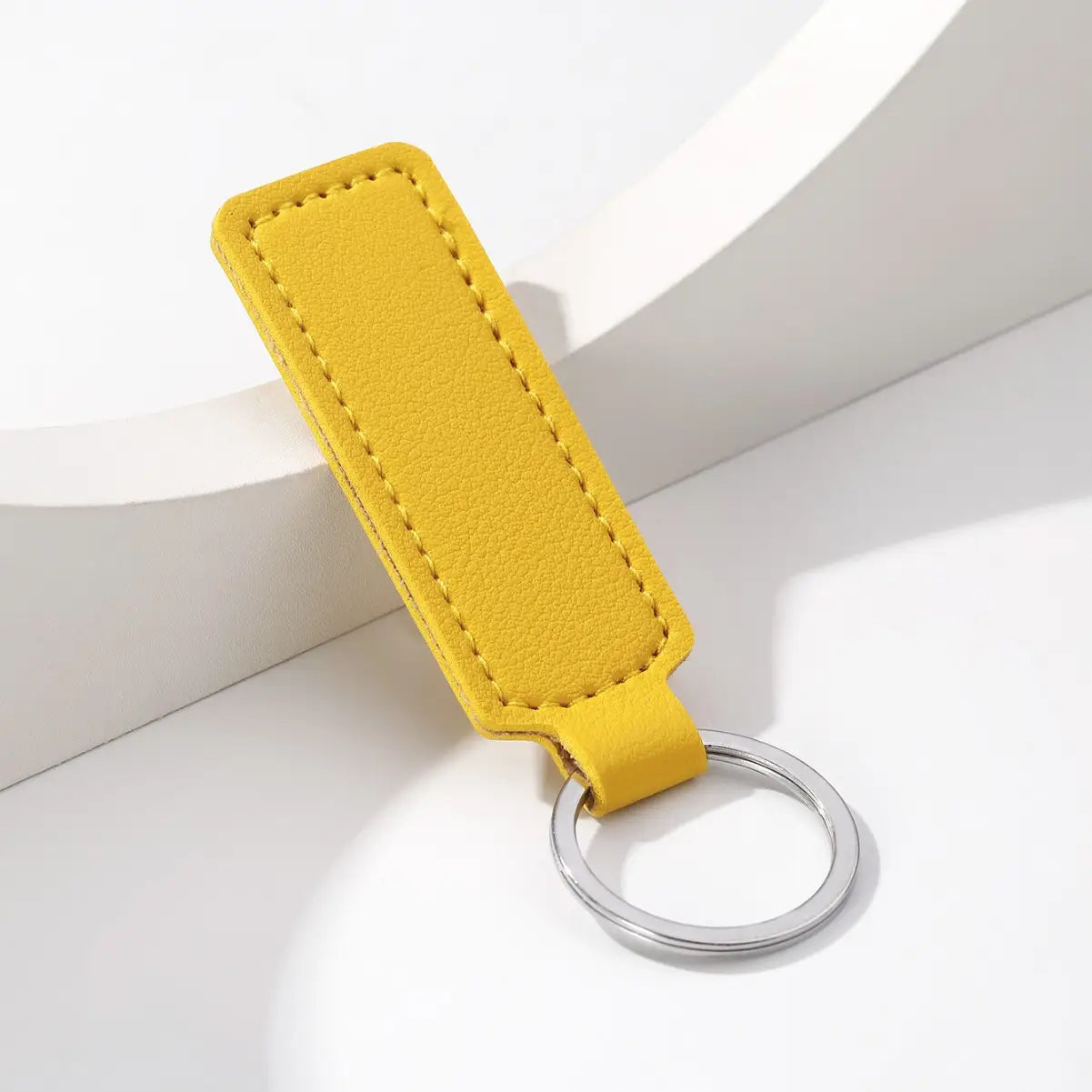 A vibrant yellow leather car keychain minimalist strip key ring with a sleek rectangular design and precise edge stitching.