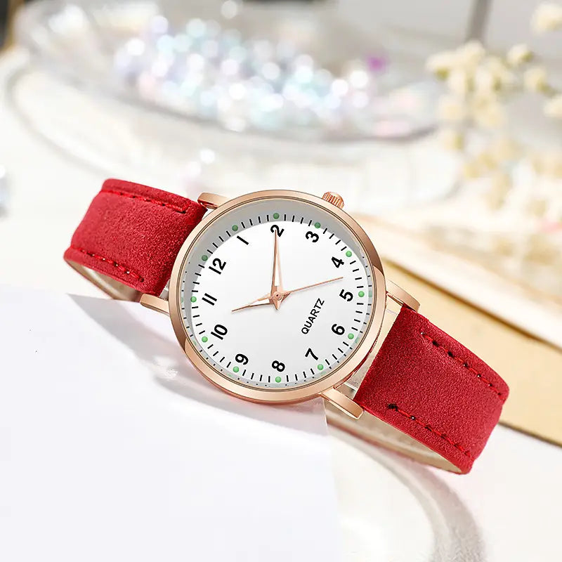 A delicate rose gold women leather quartz watch with a white dial, bold red suede strap, and green dot hour markers.