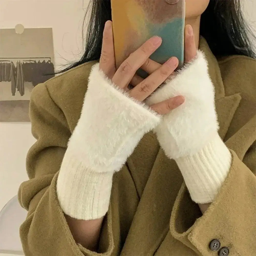 Weiße flauschige fingerlose Strickhandschuhe für Damen mit gerippten Strickbündchen und einem weich strukturierten Material.
