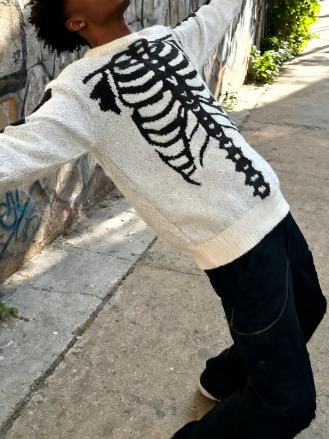 Pull gothique à jacquard squelette en maille de couleur crème pour hommes, avec un motif de cage thoracique noir audacieux du côté arrière.