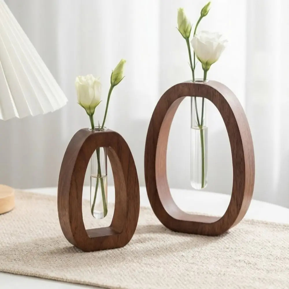 Two minimalist wooden oval vases each containing a clear glass test tube with white flowers for a wooden hydroponic glass tube vase desktop planter.
