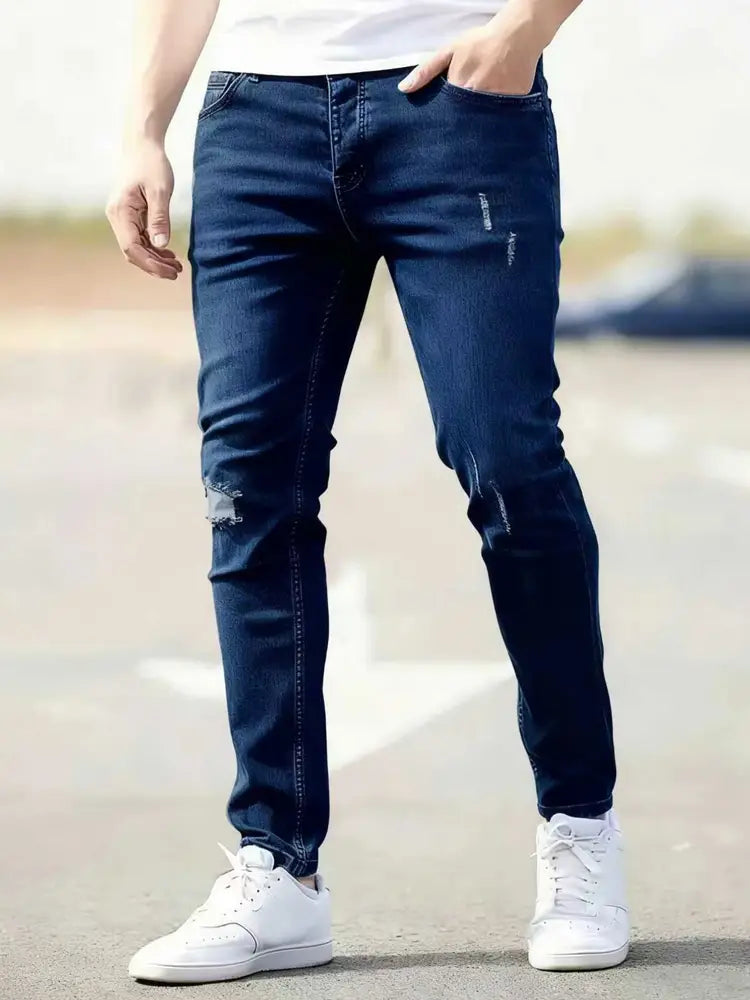 Dark blue denim men distressed skinny jeans with slim fit and vintage style featuring distressed knee patches.
