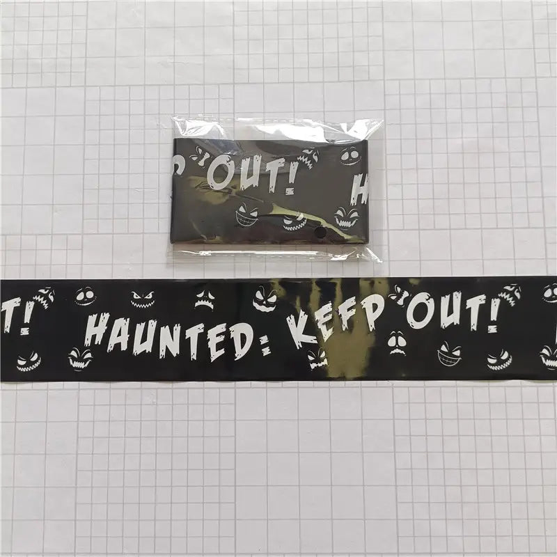 black halloween caution tape with white haunted keep out text and smiling ghost faces for spooky party warning barrier use.