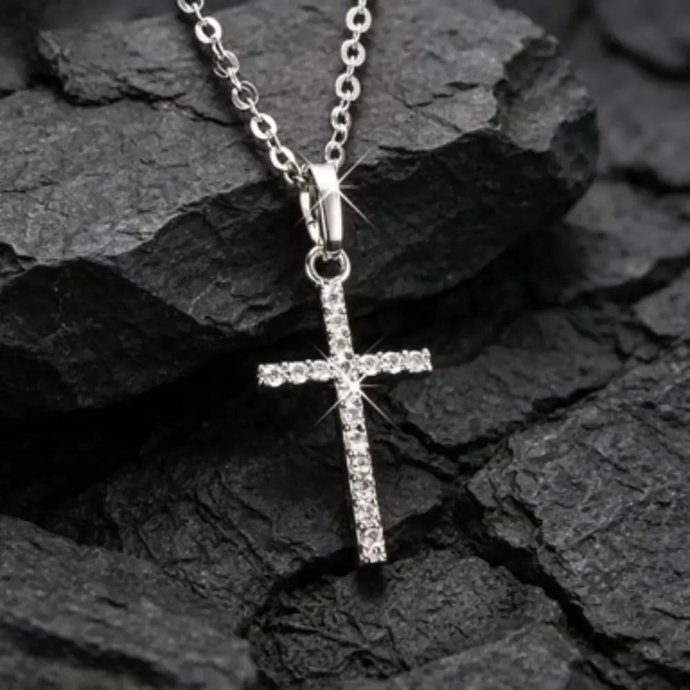 Collier en argent avec pendentif en forme de croix en cristal étincelant, présentant des cristaux intégrés sur une chaîne en argent assortie.