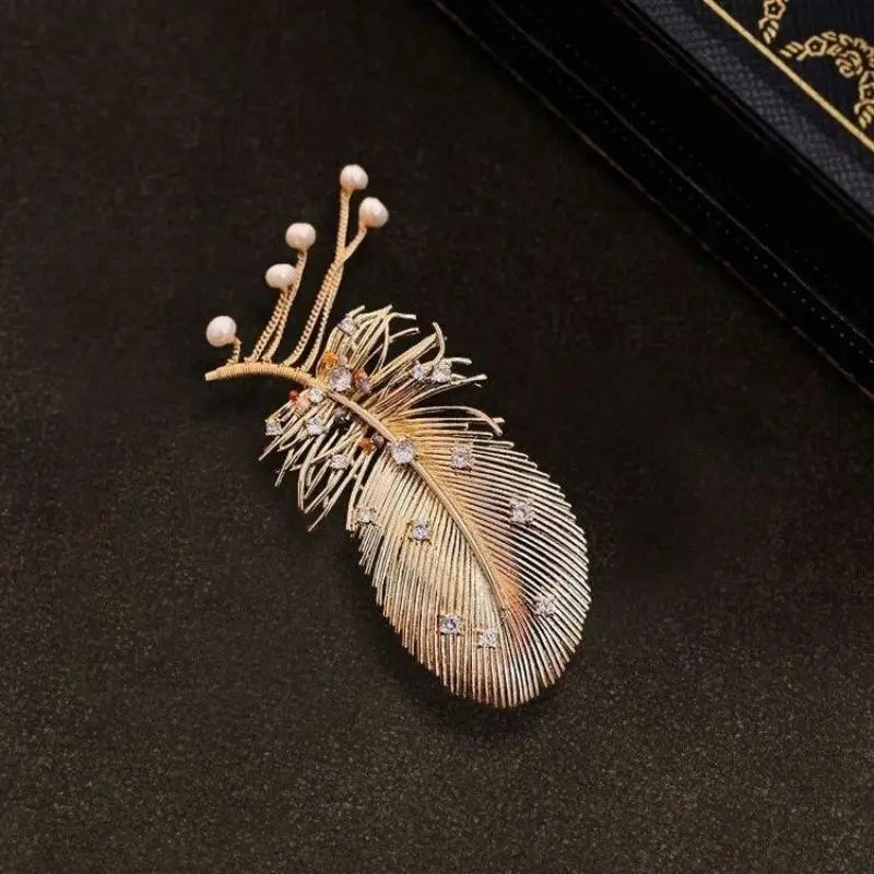 Broche à pompon en perles de plume dorée, avec métal ton or et de minuscules cristaux transparents, ainsi que de délicates perles blanches le long de la tige.