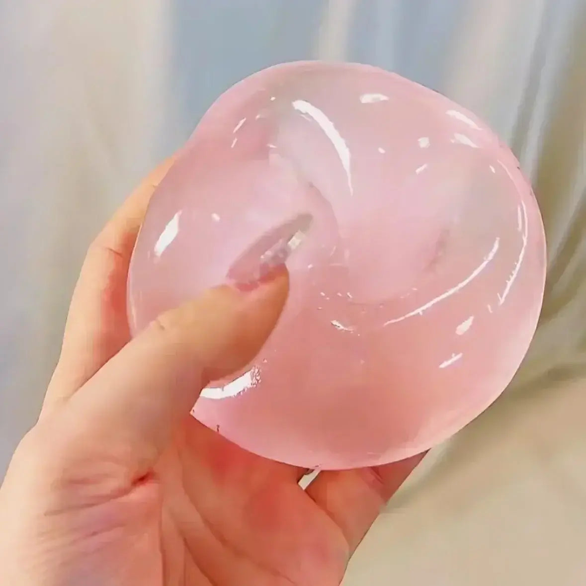 Un jouet à mâcher et à malaxer en forme de fromage gélatineux translucide rose, conçu pour soulager le stress, texture souple et molle, avec une surface lisse légèrement brillante pour apaiser le stress lié au jouet et pour la relaxation.