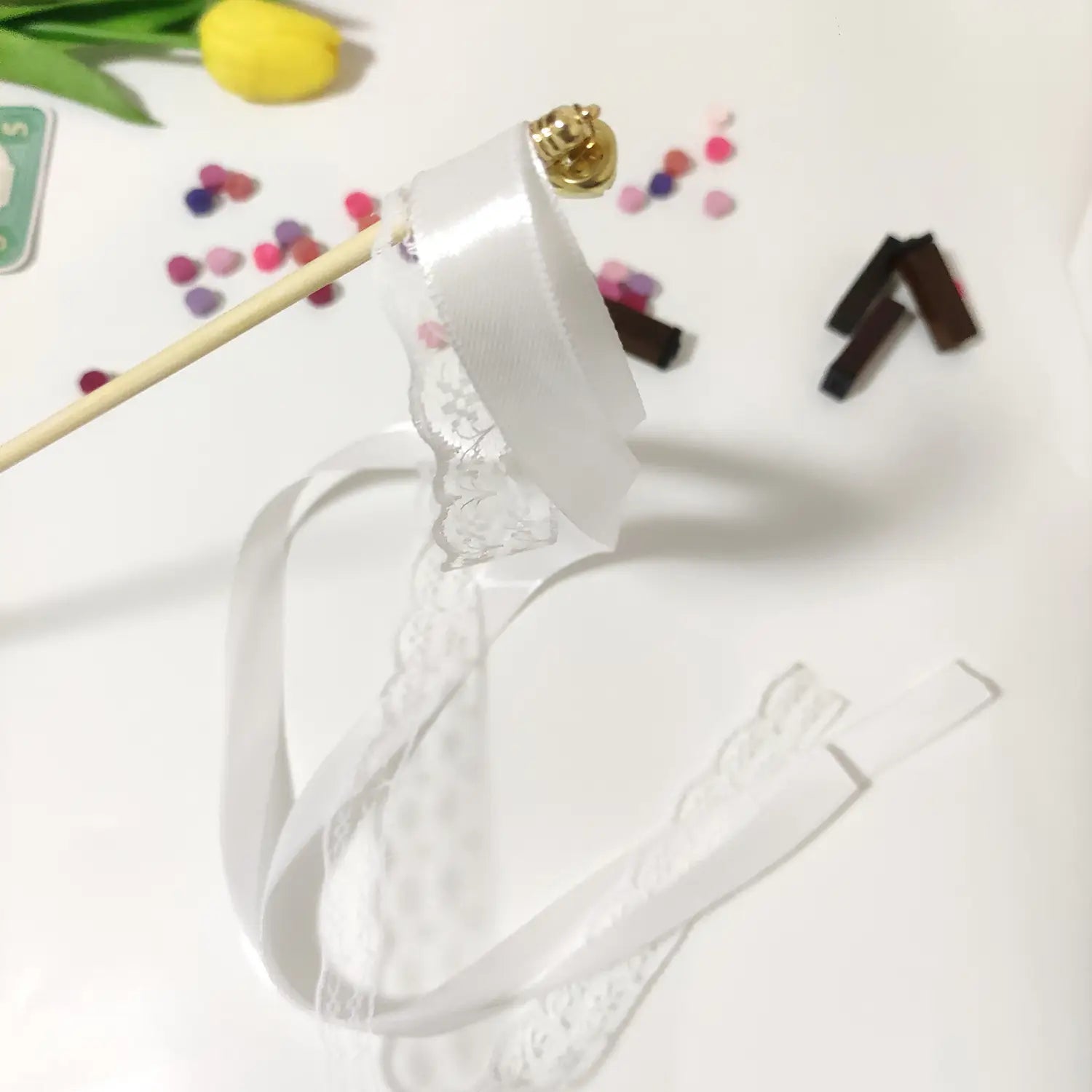 Baguette de ruban en dentelle blanche avec une cloche dorée en partie supérieure, conçue pour des baguettes de ruban de mariage avec dentelle et cloches.