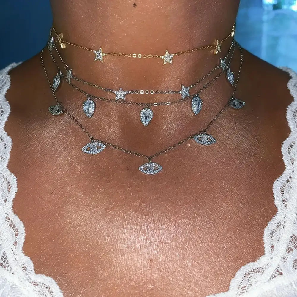 Collares tipo gargantilla en capas con cadenas en tono dorado con circonitas cz con forma de gota de lágrima, colgantes con forma de estrella y ojo, adornados con cristales transparentes.