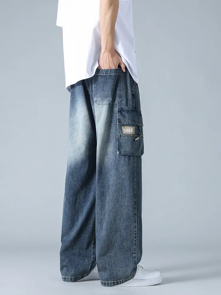 Jean cargo en denim ample pour homme, grande taille, en bleu délavé, coupe jambe large, avec des poches cargo, dont une avec un petit écusson rectangulaire.