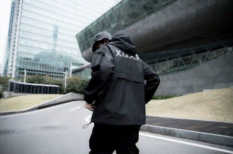 Veste tactique techwear imperméable à capuche noire avec lettrage blanc x.g.a.f sur la face arrière, conçue pour un usage en extérieur