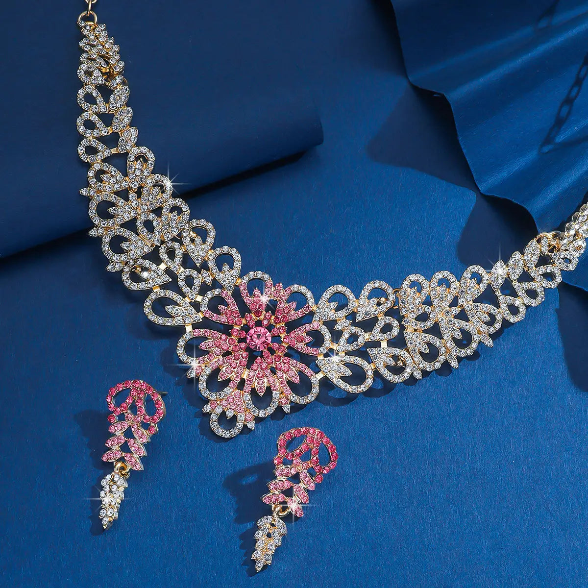 Un collier ton or étincelant issu de l’ensemble de bijoux en forme de fleur en cristal rose plaqué or, doté de motifs floraux complexes ornés de rhinestones clairs et roses.