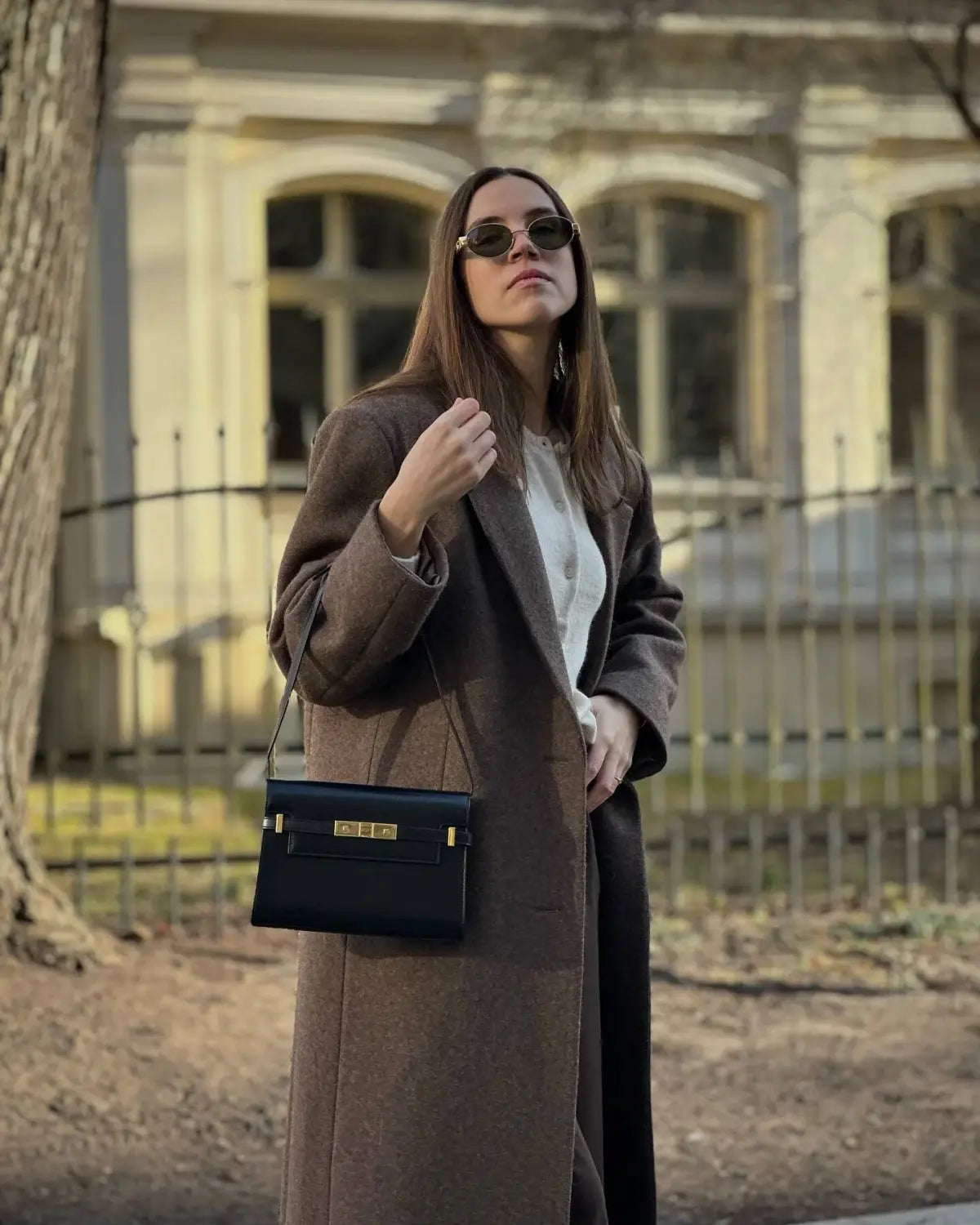 Black leather handbag with gold tone hardware and minimalist rectangular design complementing brown wool blend overcoat women winter commuter jacket.