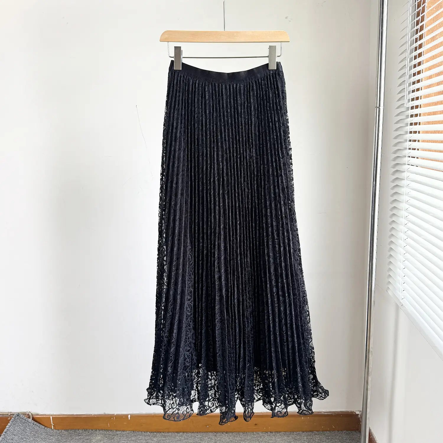black pleated lace high waist midi skirt hanging on a wooden hanger for y2k streetwear style