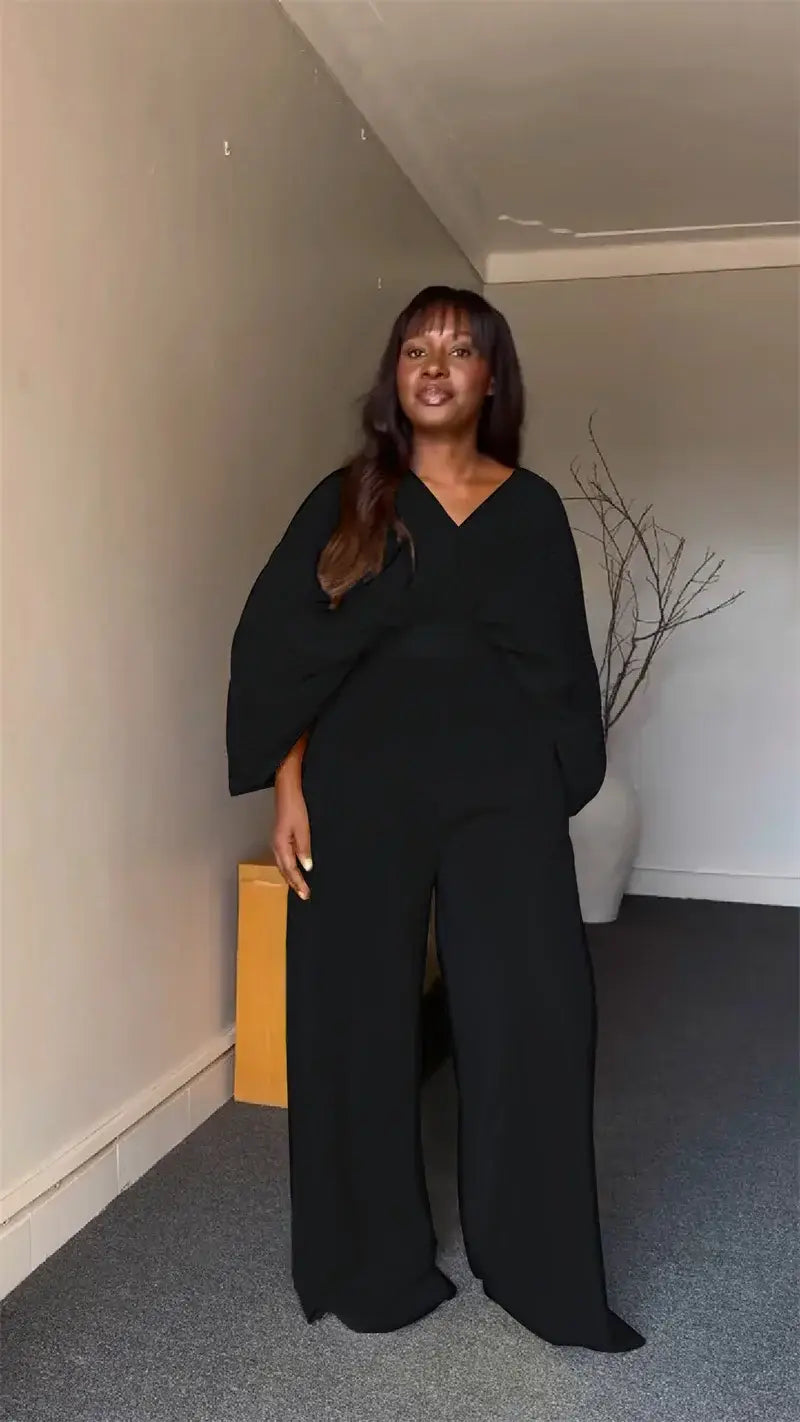 Black wide-leg jumpsuit with flowing oversized sleeves and a v-neckline featured alongside a purple satin two piece set with wide leg pants.