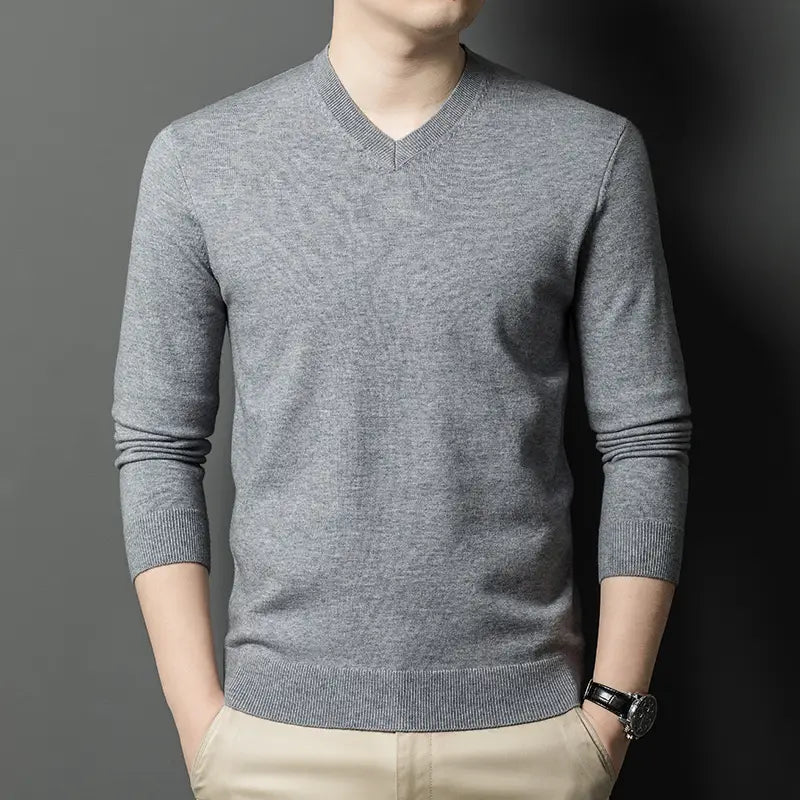 Ein Herren-V-Ausschnitt-Strickpullover in Grau mit gerippten Bündchen und Saum, gefertigt aus weichem Strickmaterial.