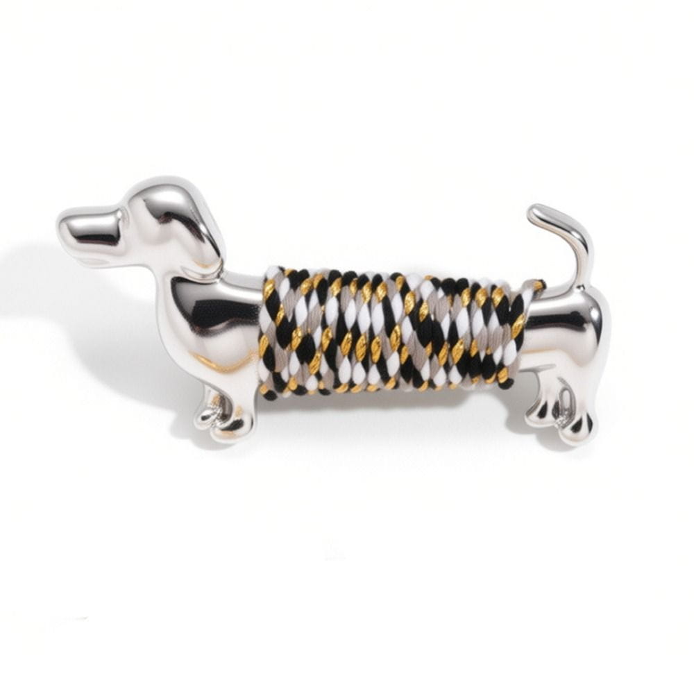 porte-clés en forme de teckel argenté, avec un corps enveloppé d’une corde tressée noire, blanche et dorée, issu de la collection de broches à revers animalières dorées en forme de teckel.