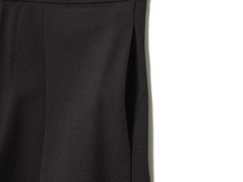 Pantalons taille haute plissés à jambes évasées noirs en tissu lisse et structuré, offrant un tombé élégant et un joli mouvement