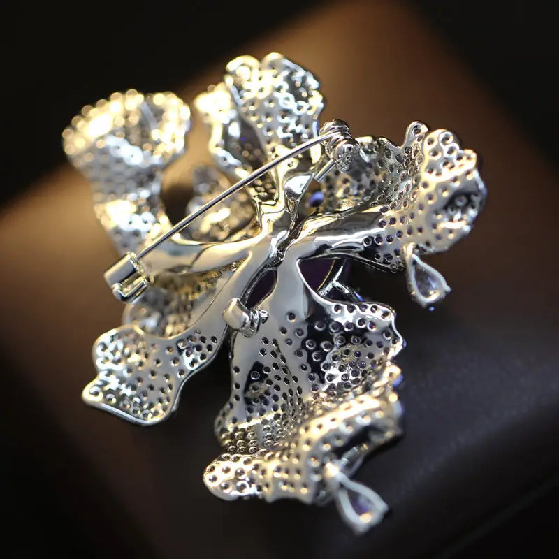 Broche de flor con filigrana en tono de plata, con detalles intrincados tipo encaje e incrustaciones de gemas violetas en un broche de mariposa de zirconio, pin de lujo de diseñador.