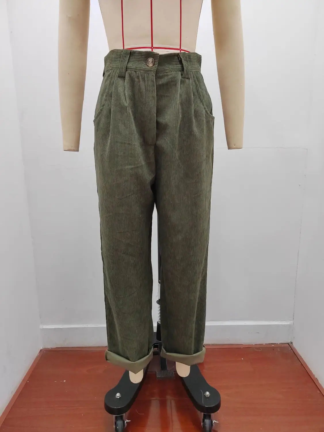 Pantalon en velours côtelé vert olive taille haute ample avec bas retroussés, présenté de face.