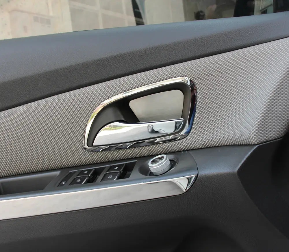 Manija de la puerta con acabado en cromo y diseño moderno y elegante en el interior de Chevrolet Cruze 2009-2014, con moldura de tela gris texturizada.