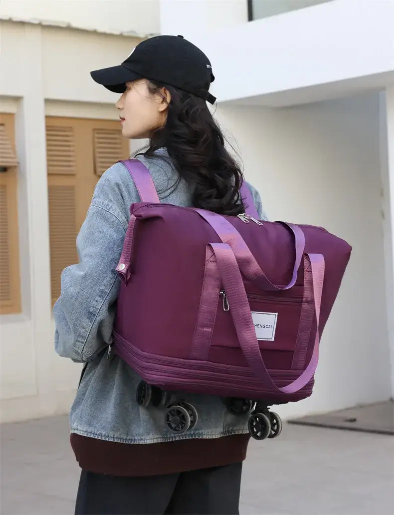 Un sac duffel roulant violet à grande capacité, avec des sangles assorties et une petite étiquette blanche, conçu pour le voyage.