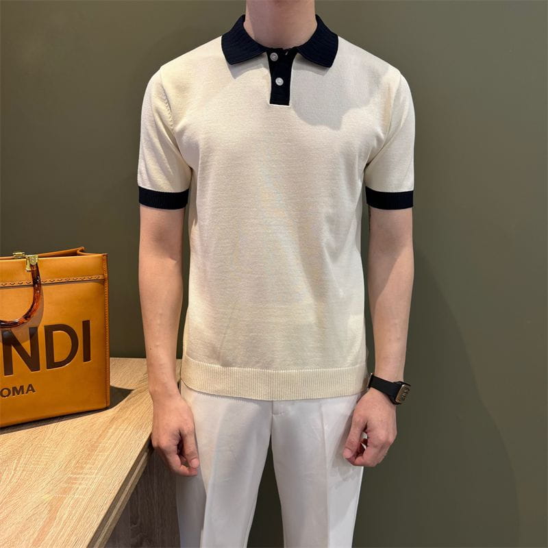 Camiseta tipo polo de punto color crema con cuello negro y puños de las mangas, con diseño de bloques de color.