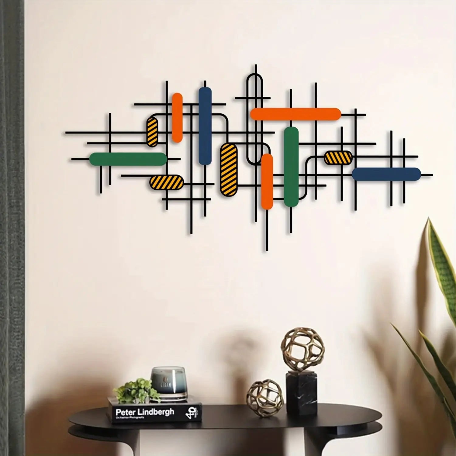 Colorful geometric metal wall art features intersecting black metal lines and colorful rectangular bars in orange green blue and striped yellow brown as modern wall decor.