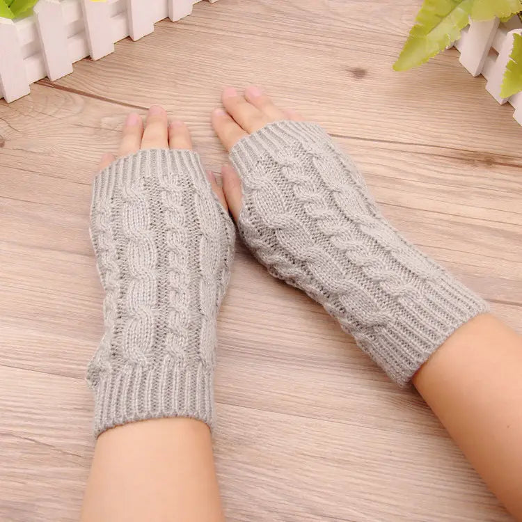 Graue, gestrickte Damen-Handschuhe ohne Finger mit Zopfmuster, geeignet für die Nutzung im Winter.