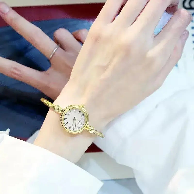Gold-toned stainless steel quartz bangle watch for women featuring a rope-style band and a round white face with roman numerals.