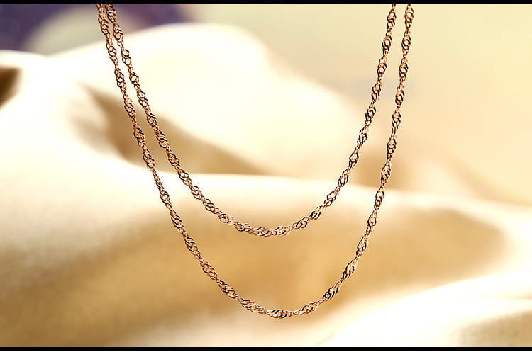 Un collar de cadena delicado con baño de oro y eslabones trenzados, con un diseño clásico y elegante, que forma parte de un collar de moissanita en plata de ley con tono oro rosa.