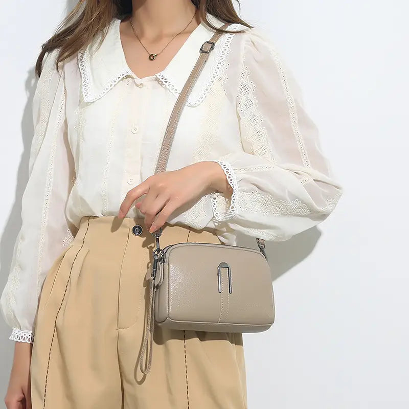 Beige Umhängetasche aus echtem Leder für Damen mit einem schlanken, rechteckigen Design und silberfarbenem Metallschnallenverschluss.