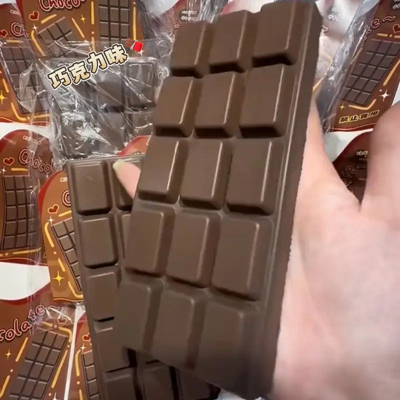A dark brown segmented chocolate bar squeeze toy with a smooth glossy surface and classic square divisions designed as a slow rising sensory fidget.