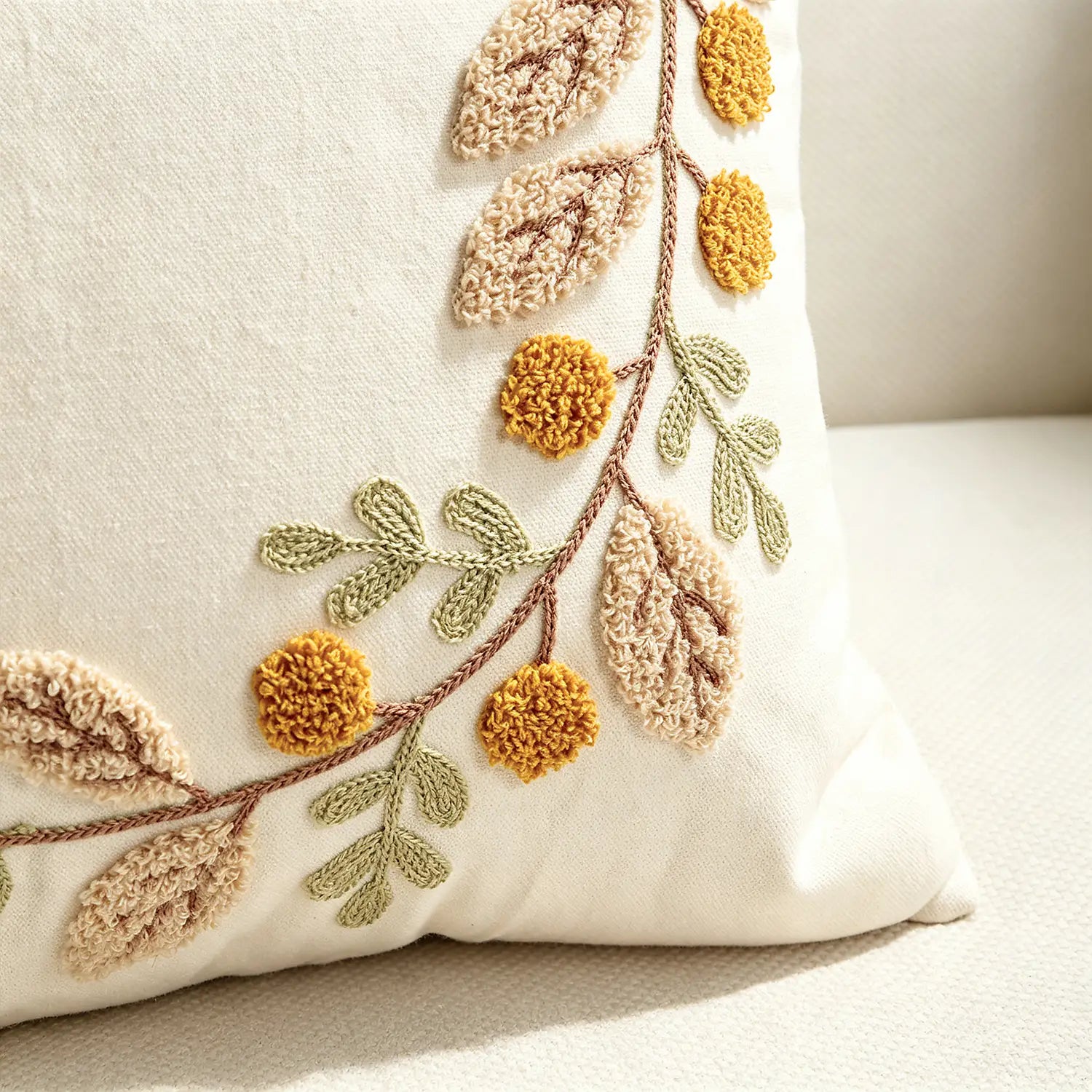 Housse de coussin d’appoint de couleur crème avec un feuillage brodé texturé dans des tons beige, jaune moutarde et vert olive, adaptée aux housses de coussin et à la décoration d’automne.