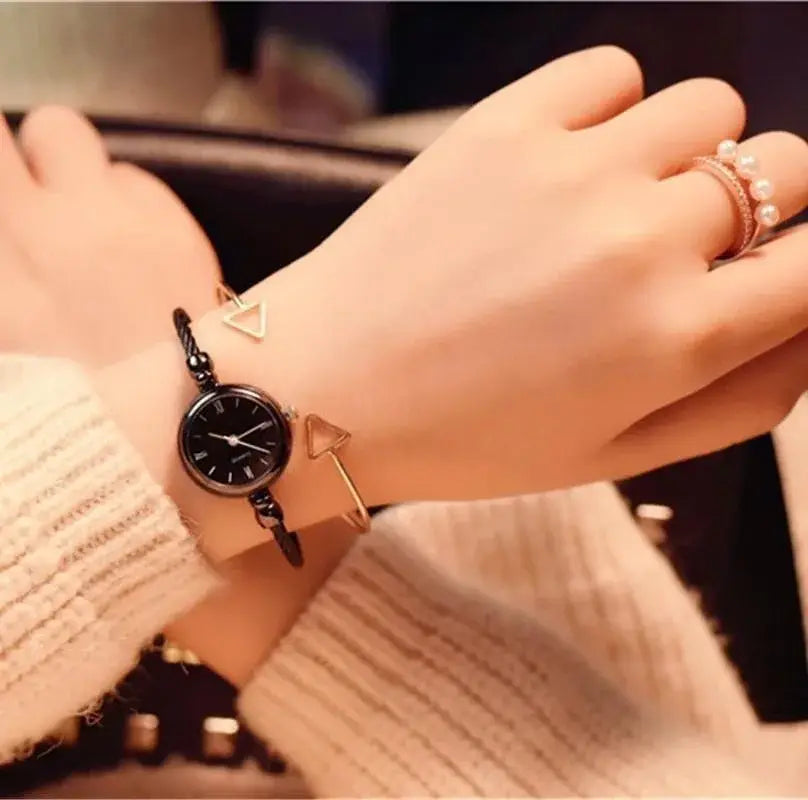Women stainless steel quartz bangle watch featuring a black round face with a braided black cord and gold triangle charms.