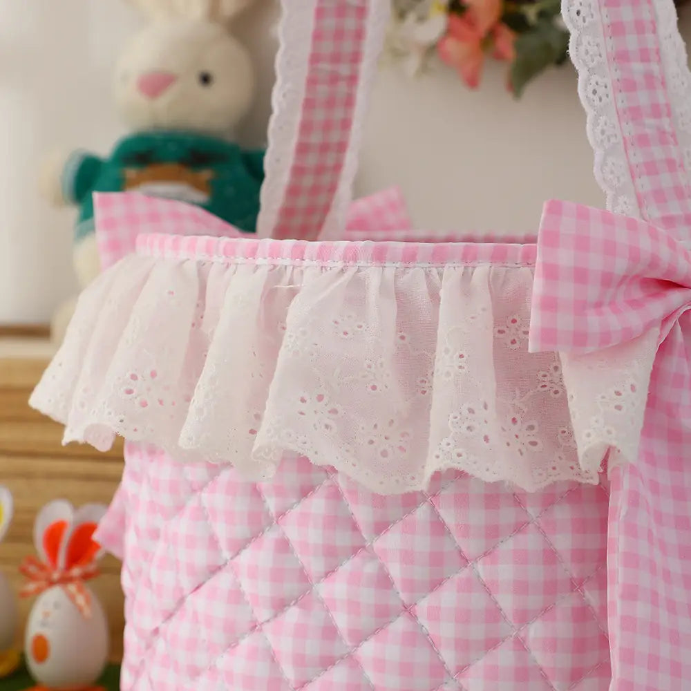 pink gingham Easter basket made of quilted fabric with white and pink checkered pattern, featuring a delicate lace ruffle trim and matching bow.