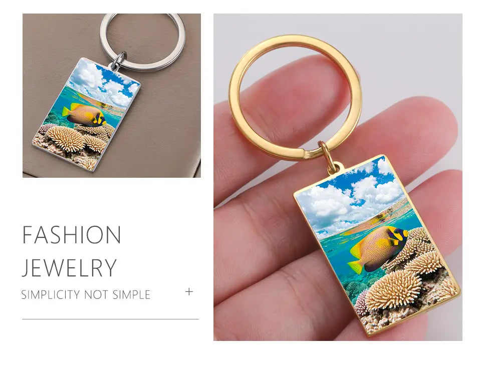 custom photo rectangle keychain with stainless steel ring featuring a gold-toned frame and a vivid underwater scene with a yellow and black fish swimming above textured coral against a blue sky backdrop.