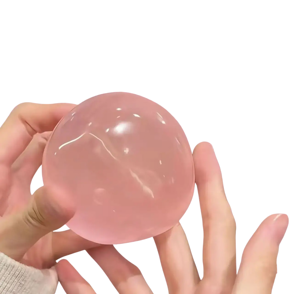 A translucent pink blue coconut oil stress ball squeeze toy with a smooth glossy surface held gently in hands