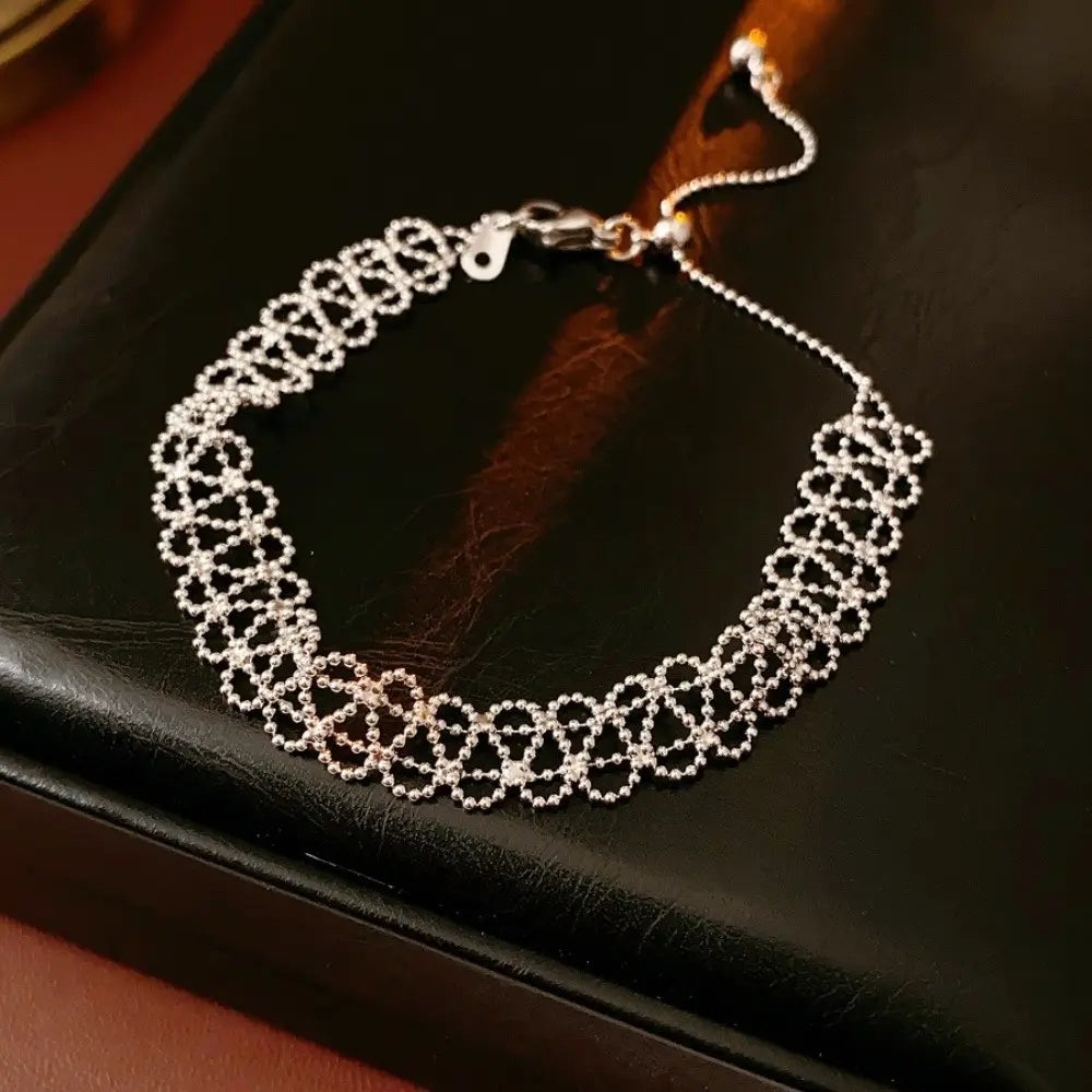 Silver metal lace bracelet with beaded design featuring an intricate lace-like pattern and an adjustable clasp for versatile fashion jewelry use