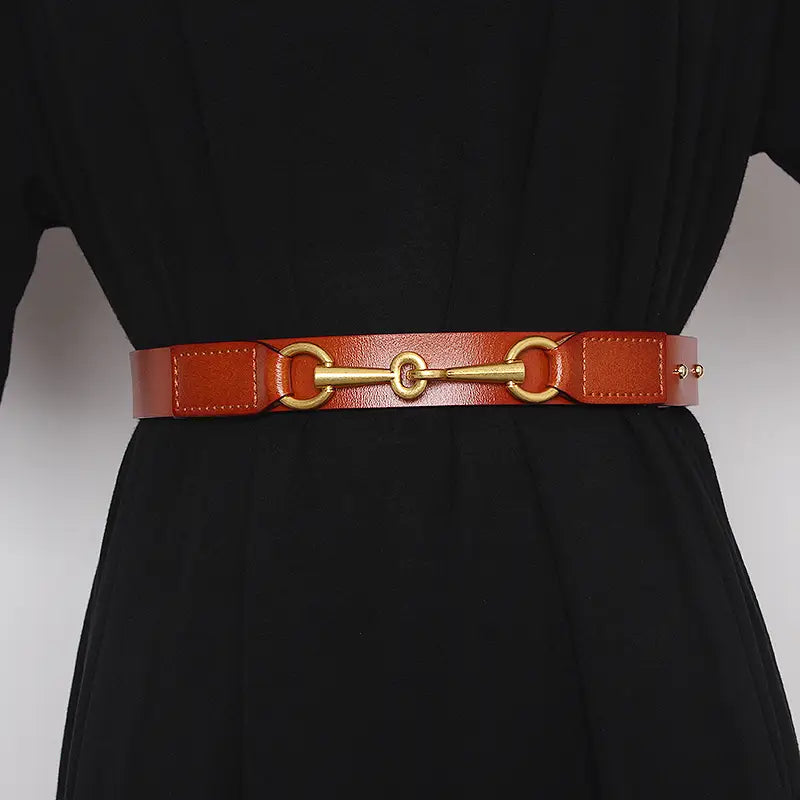 A sleek tan leather women leather belt featuring a polished gold-tone horsebit buckle.