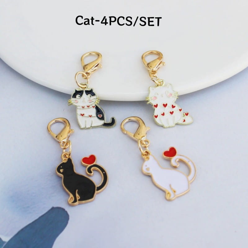 Four enamel cat keychains with black and white designs, red heart accents, and gold-toned clasps, decorative cute charms.
