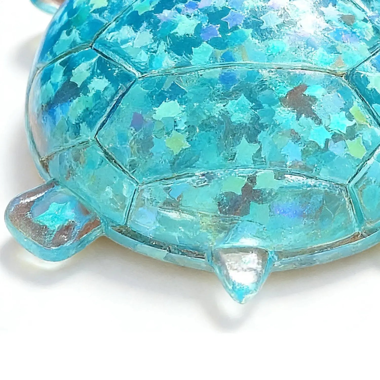 A translucent turquoise resin squeeze toy in turtle shape with embedded star-shaped glitter designed as a sensory fidget.