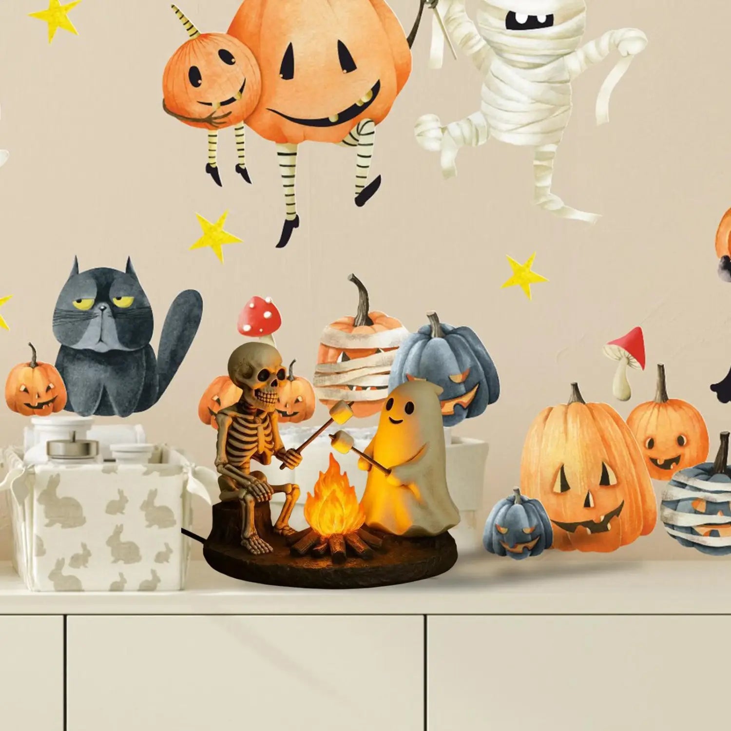 la lanterne de nuit de feu de camp fantomatique thématique Halloween : elle présente un fantôme squelette et des figurines de fantômes rôtissant des guimauves près d’un feu de camp lumineux, entouré de citrouilles et de personnages effrayants.