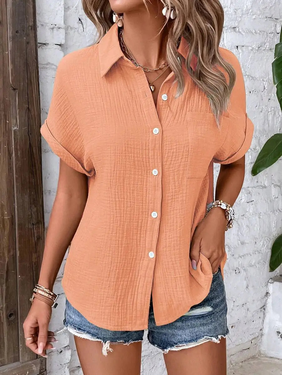 A soft peach-colored women cotton short sleeve button up shirt featuring a subtle textured fabric and rolled cuffs.