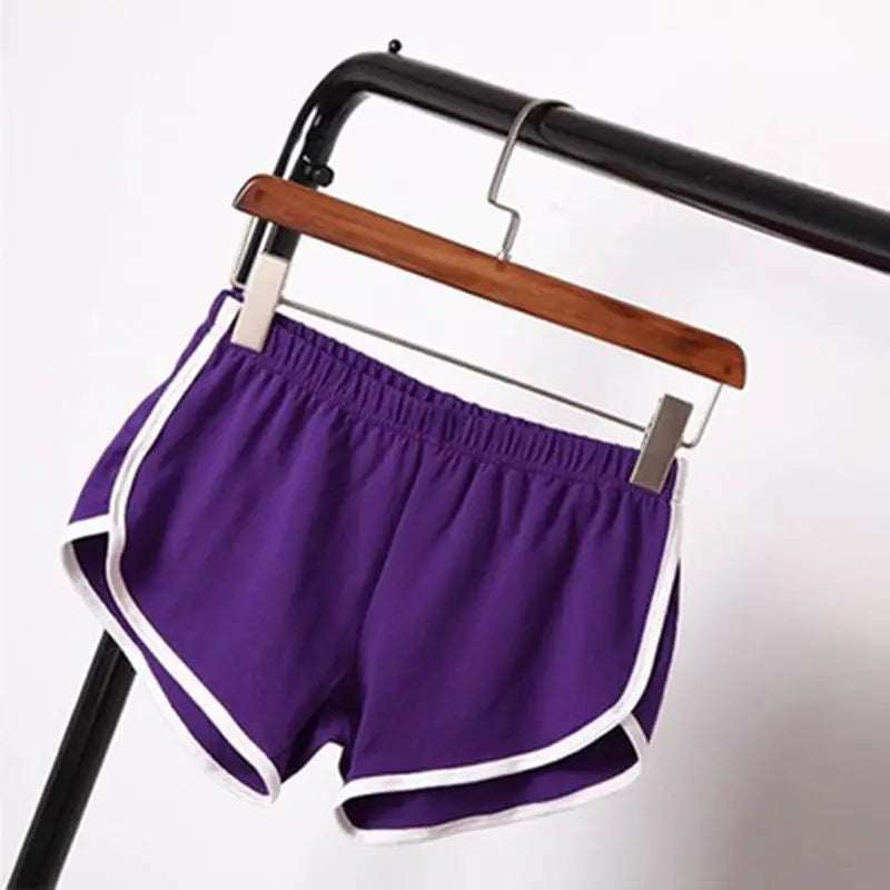 purple sports shorts women with white trim and elastic waist hanging on a wooden hanger designed for casual athletic use