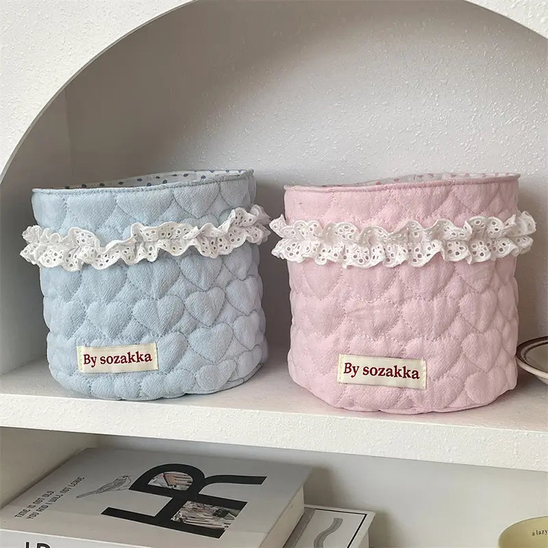Pastellblaue und -rosafarbene gepolsterte Aufbewahrungskörbe aus Stoff mit weißem Spitzenbesatz und von Sozakka-Schildern zur Organisation im Kinderzimmer.