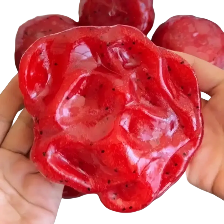 A front view of a handmade vibrant red dragon fruit squishy toy with textured surface and black seed details