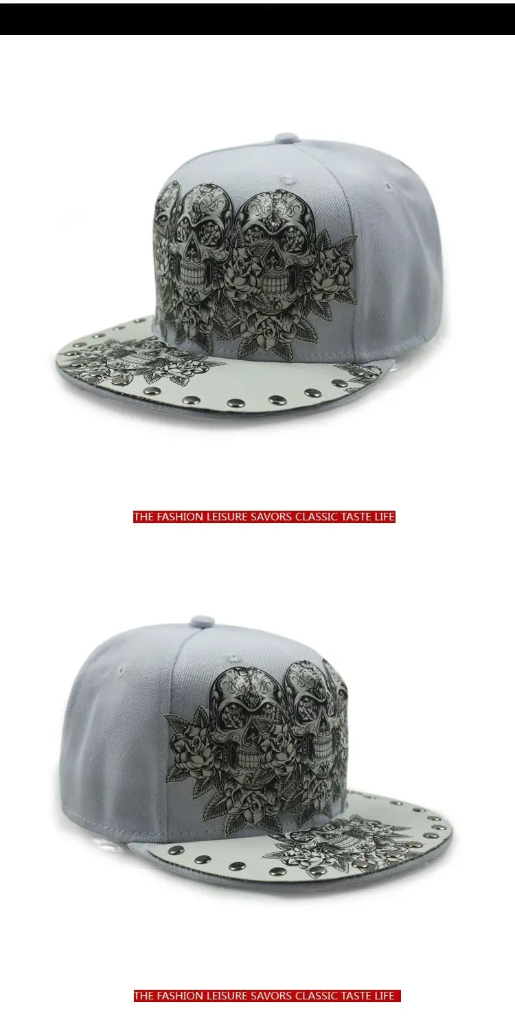 Gray snapback baseball cap featuring a black and white tattoo-style sugar skull design with floral patterns and silver studs along the brim.