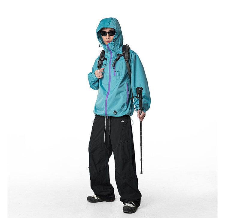 chaqueta impermeable con capucha color verde azulado, con acentos en cremallera morados, combinada con pantalones cargo impermeables de senderismo diseñados para secado rápido y actividades al aire libre.