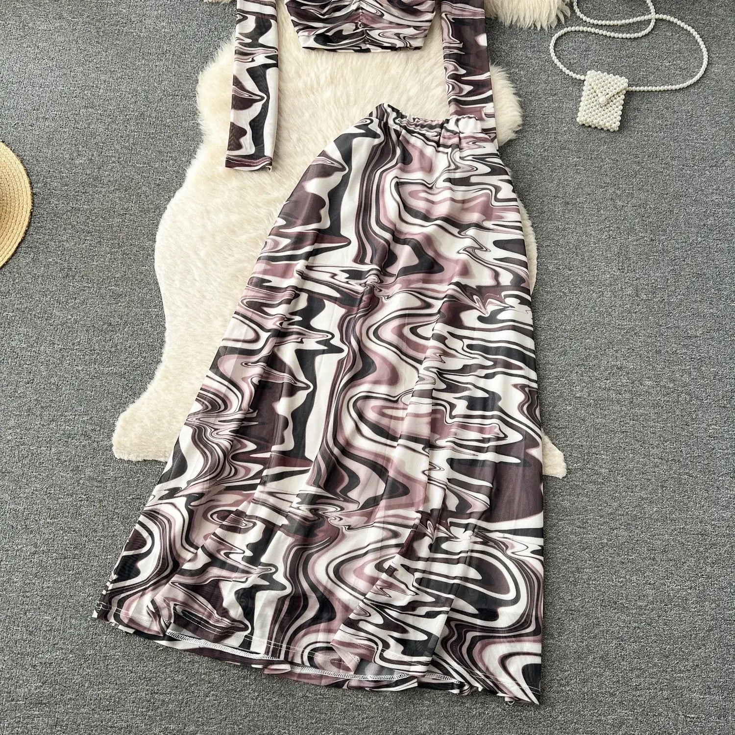 A flowing midi skirt from a two piece mesh skirt set featuring a bold abstract marbled pattern in black white and muted pink with an elastic closure.