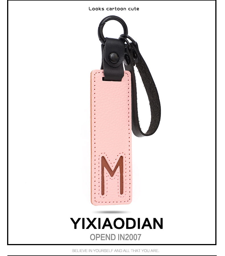 Pink leather letter keychain with embossed brown letter m, black strap, and metal ring suitable as an alphabet pendant party gift.